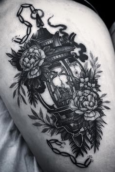 a woman's thigh with flowers and a lantern on it