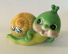 a little green snail figurine sitting on top of a banana