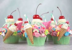 four cupcakes with ice cream, cherries and candy on top are shown