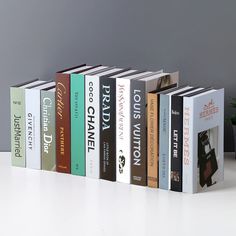 a row of books sitting on top of a white table next to a potted plant