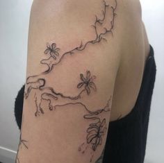 a woman with a tattoo on her arm that has vines and flowers growing out of it