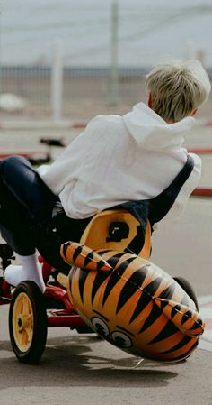 a young boy riding a tricycle with an inflatable tiger design on the back