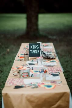 a long table covered in lots of different items on top of a grass covered field