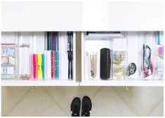 a pair of black shoes sitting on top of a white shelf filled with office supplies