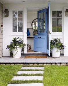 a blue door is open on a white house with steps leading up to the front door