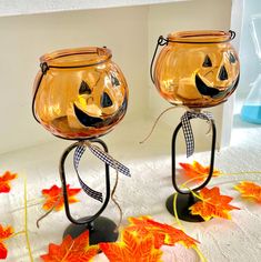 two pumpkin shaped glass candlesticks with faces on them