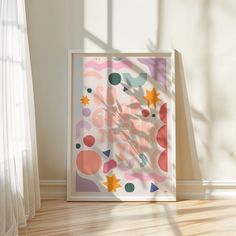 an abstract painting on the floor in front of a window with sunlight coming through it