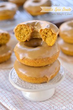 a stack of doughnuts sitting on top of a white cake plate covered in frosting