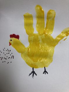 a child's handprint made to look like a yellow chicken with black feet