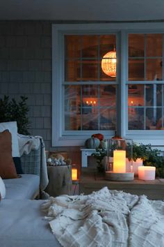 a living room with candles on the table and blankets on the couch in front of it