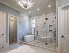 a bathroom with a tub, chandelier and glass shower door in the corner