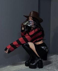 a woman in black boots and a red striped sweater is sitting on the floor with her legs crossed