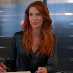 a woman with red hair sitting at a desk