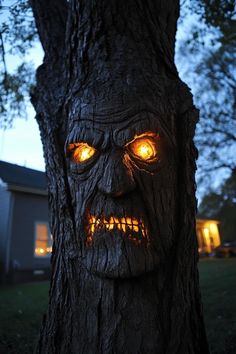 a tree with glowing eyes and a scary face on it's trunk in front of a house