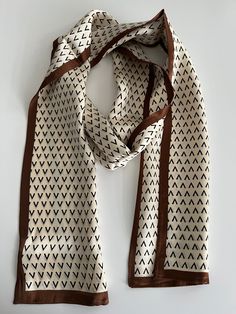 Very pretty and neat silk scarf, a cream base with a brown/caramel border, and a black geometric design.    - 100% pure high-quality mulberry silk. - Double-sided, Luxurious, and lightweight - Perfect accessory for any occasion and outfit and any season - One-of-a-kind design. - Great gift idea for any occasion  - Free Gift wrapping option available - 53.5X7 inches Care Instructions: Hand-wash your silk scarf in cold water with mild detergent. Rinse with water until all the soap is removed.  Bal Traditional Beige Silk Scarves, Elegant Beige Square Silk Scarf, Traditional Brown Silk Scarves, Elegant Brown Silk Scarf One Size, Elegant Brown Rectangular Silk Scarf, Luxury Brown Silk Scarf, Silk Hair, Luxury Silk, Free Gift Wrapping