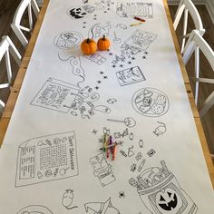 a long table covered in drawings and pumpkins on top of white paper with markers