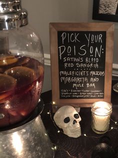 a table topped with a sign next to a cup filled with liquid and a skull head