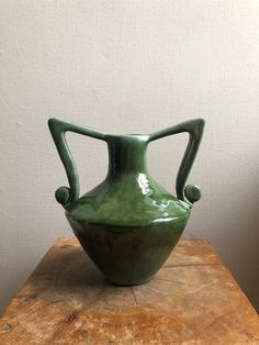 a green vase sitting on top of a wooden table