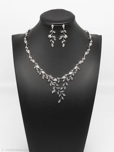 a necklace and earring set on a mannequin neckline with leaves in the center