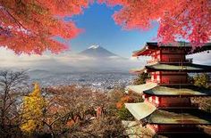 the pagodas are surrounded by trees with red leaves on them and mount fuji in the background