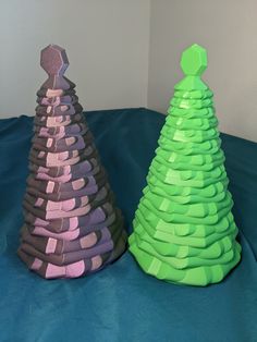 two paper christmas trees sitting on top of a blue sheet