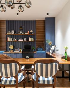 two chairs sit in front of a wooden table with blue and white striped upholstered chairs