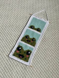 a cross - stitch bookmark with four images of bears on it, hanging from a needle