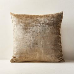 a gold velvet pillow sitting on top of a white table