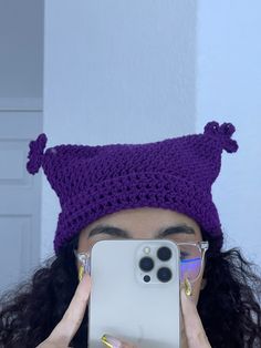 a woman taking a selfie in front of her cell phone wearing a knitted hat