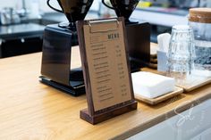 a menu sitting on top of a wooden table next to two coffee pots and cups