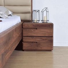 a bed sitting next to a night stand on top of a wooden floor