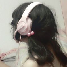 a girl with long hair wearing headphones on her face and looking at the wall