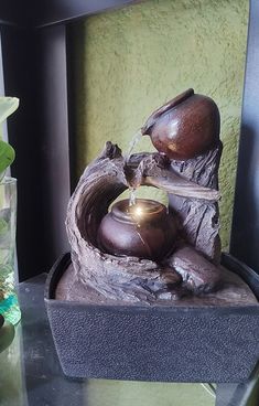 a fountain with two pots on top of it next to a vase filled with flowers