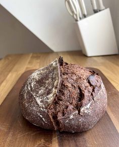 a loaf of bread sitting on top of a wooden cutting board next to utensils