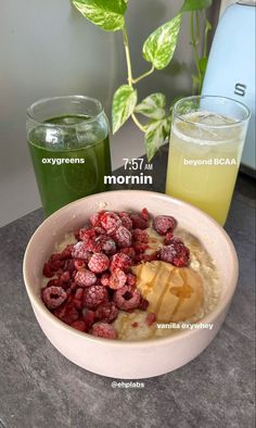 a bowl filled with oatmeal and raspberries next to two drinks