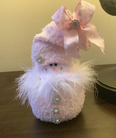 a white stuffed snowman sitting on top of a wooden table