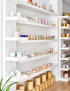 the shelves are filled with many different types of cups and vases on them,