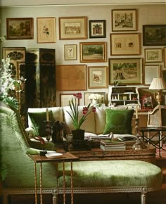 a living room filled with green furniture and pictures on the wall above it's coffee table