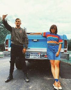 two people standing in front of a blue pick up truck