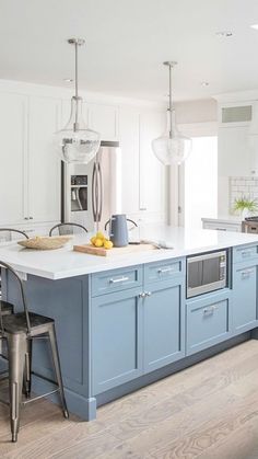 a kitchen with white cabinets and blue island