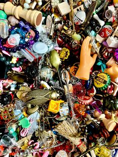 a pile of assorted beads and other items on top of each other with one hand reaching for the bead