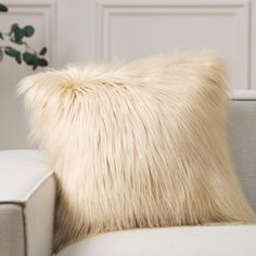 a white pillow sitting on top of a couch next to a plant