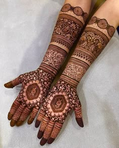 two hands with henna tattoos on them, one is showing off the intricate design