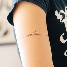 a woman with a tattoo on her arm that reads elms in cursive writing