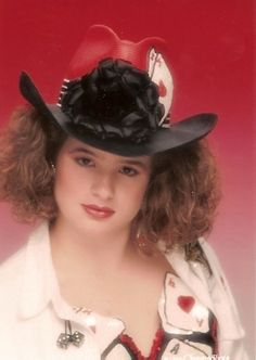 a woman wearing a black hat with a red bow on it's brim