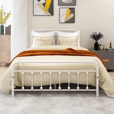 a white bed sitting in a bedroom next to two pictures on the wall above it