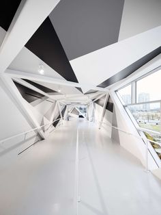 an empty white room with black and white geometric designs on the ceiling, along with large windows