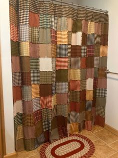 a bathroom with a rug on the floor and a shower curtain made out of patchwork