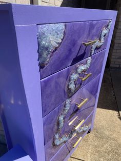 a purple dresser with blue paint and gold handles