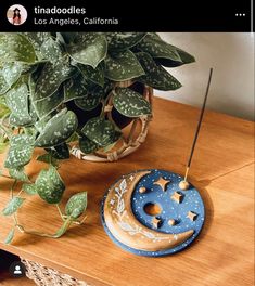 a wooden table topped with a plant and a blue moon shaped object next to a potted plant